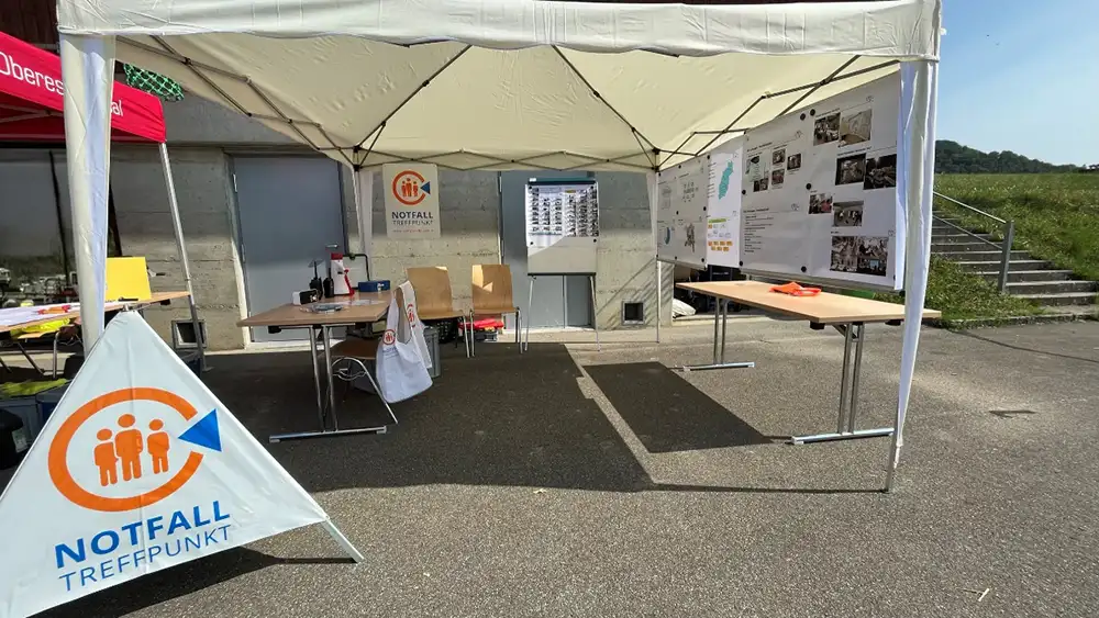 Informationsstand eines Notfalltreffpunkts mit Zelt und Aufsteller